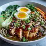 Two steaming Healthy Miso Chicken Noodle Bowls topped with sesame seeds, scallions, and chili oil beside chopsticks.