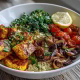 Healthy vegan scrambled tofu breakfast bowl featuring garlicky mushrooms, sautéed kale, and couscous topped with fresh avocado and parsley.