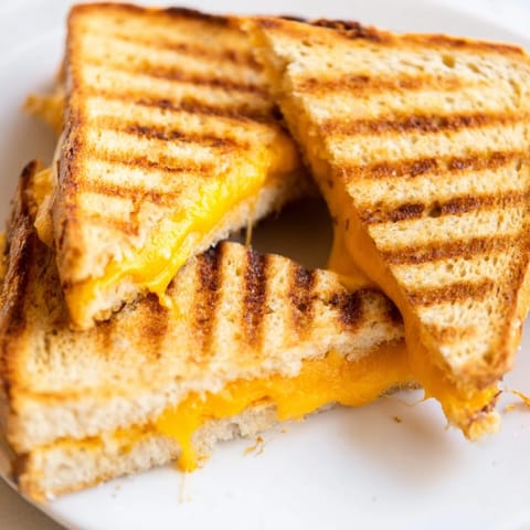 Buttery Grilled Cheese Sandwich slices on a skillet, featuring perfectly melted cheese peeking through crispy toasted bread.