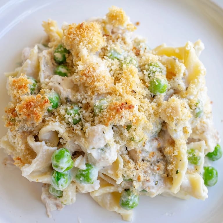 Freshly baked tuna casserole served in a dish with melted cheddar and parsley garnish, ready for dinner.