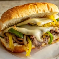Golden, melted provolone blankets savory ribeye steak and caramelized onions inside a toasted hoagie roll.