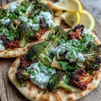 Roasted harissa broccoli and flatbreads topped with creamy yogurt and fresh cilantro, creating a spicy vegetarian dinner.